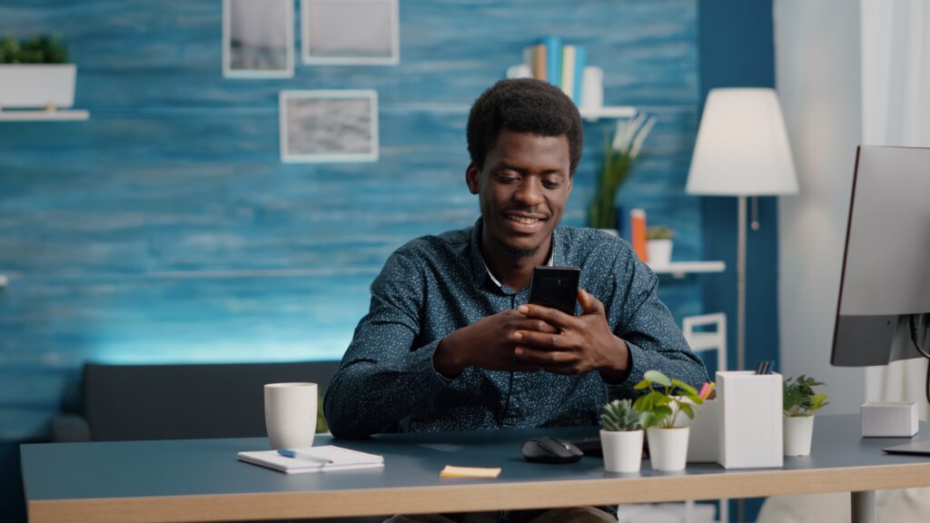 Black man in living room enjoying social media content on phone