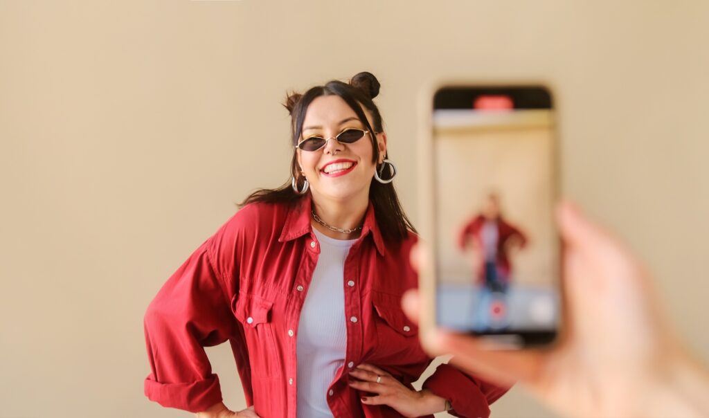 Stylish trendy woman recording dance video for social media account on phone.